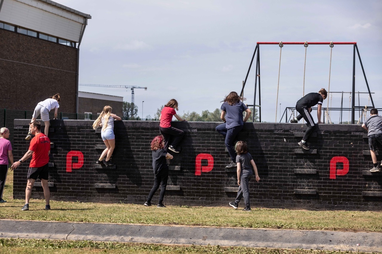 People climbing over wall on the playground assault course